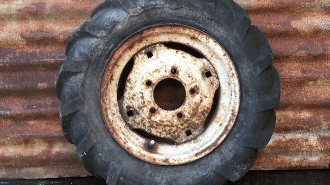 Old tire leaning on a rusted wall.